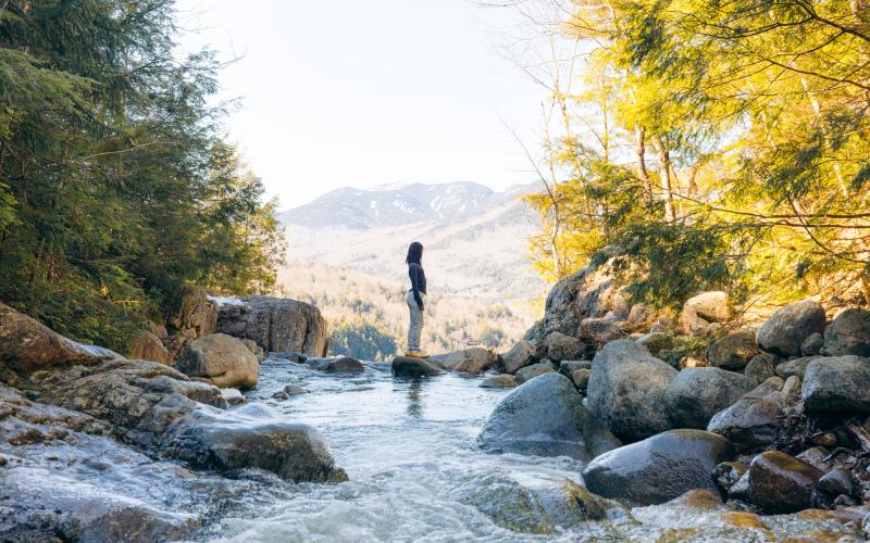 A woman stands on top of a waterfall