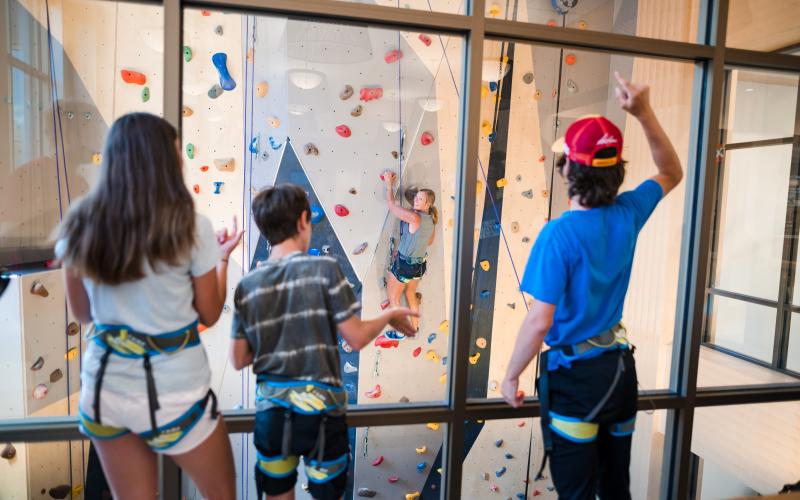 Family watches a family member climb the the climbing wall