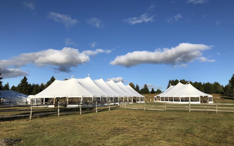Fall color sweeps through the meadow offsetting the large white tents of the wedding celebration