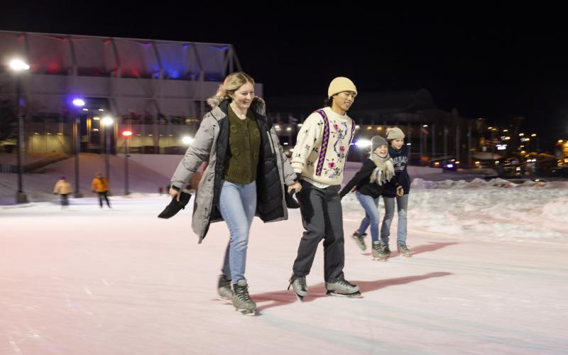 A couple skates at night on the Lake Placid Speed Skating Oval