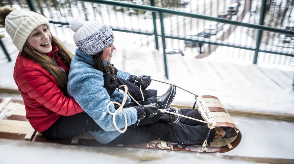 Two kids slide down the toboggan chute in Lake Placid NY