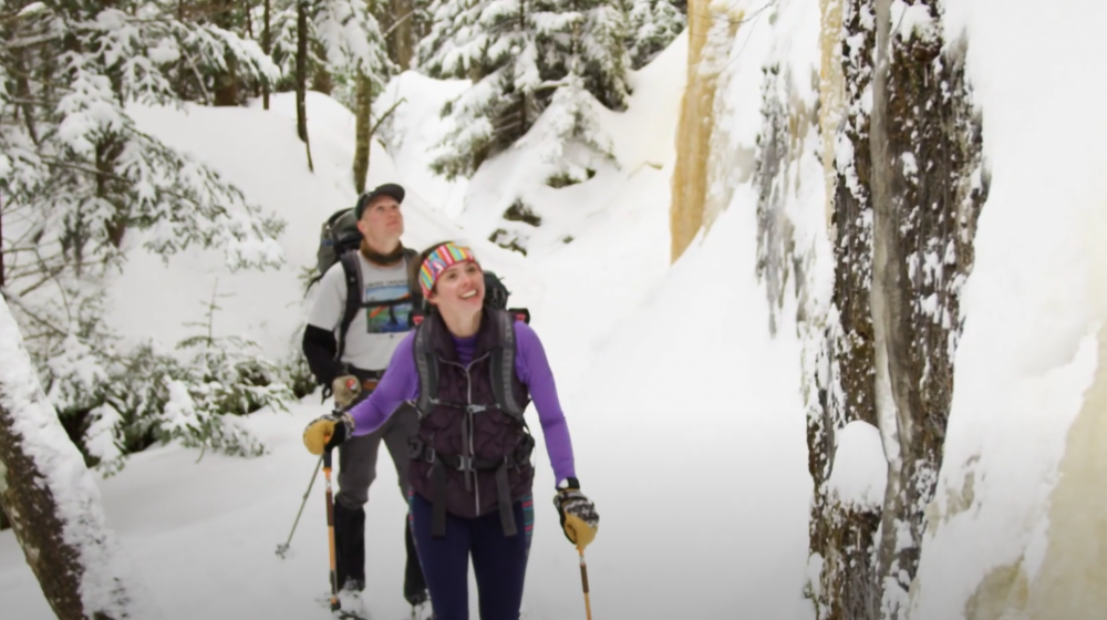 Couple looks at ice formations while snowshoeing