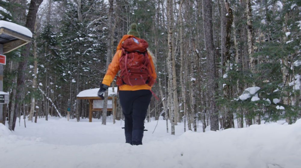 Hiker heads into a trail with fresh snow on the ground