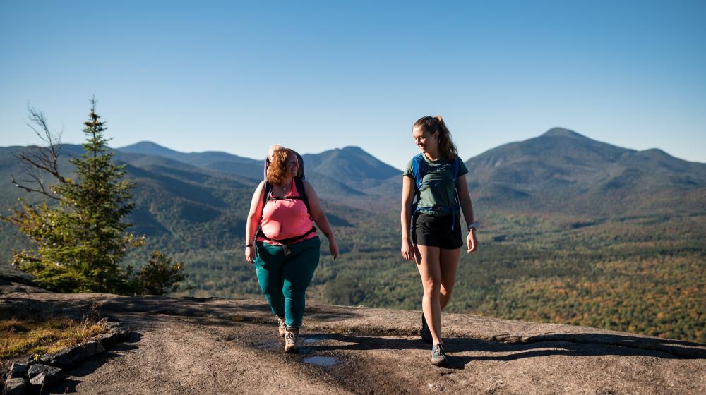 two women walk on top of a mountain.