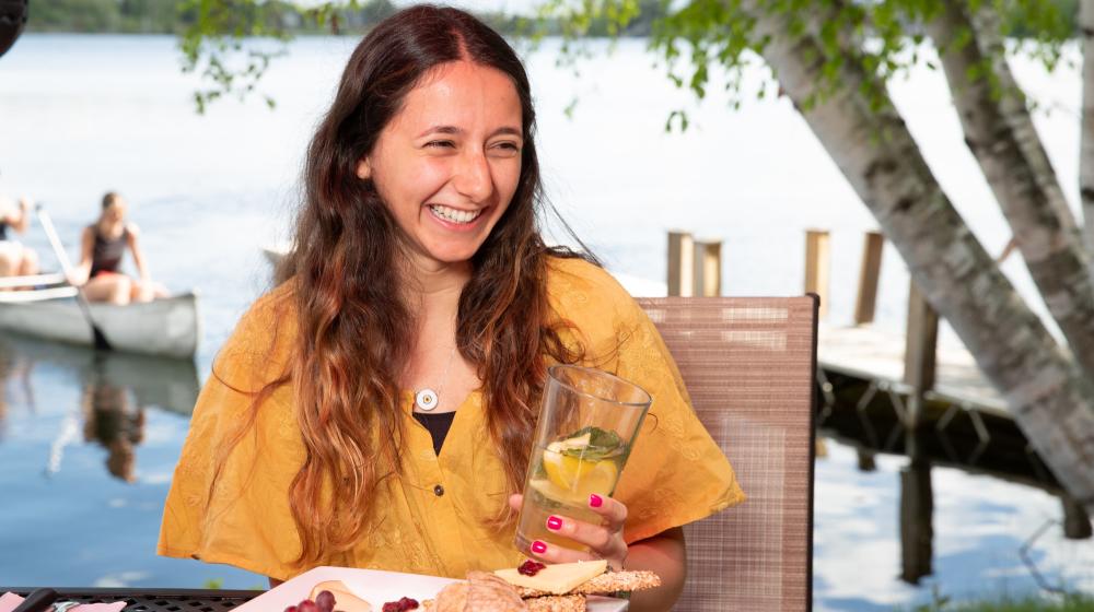 A woman laughs as she holds a beer outside.